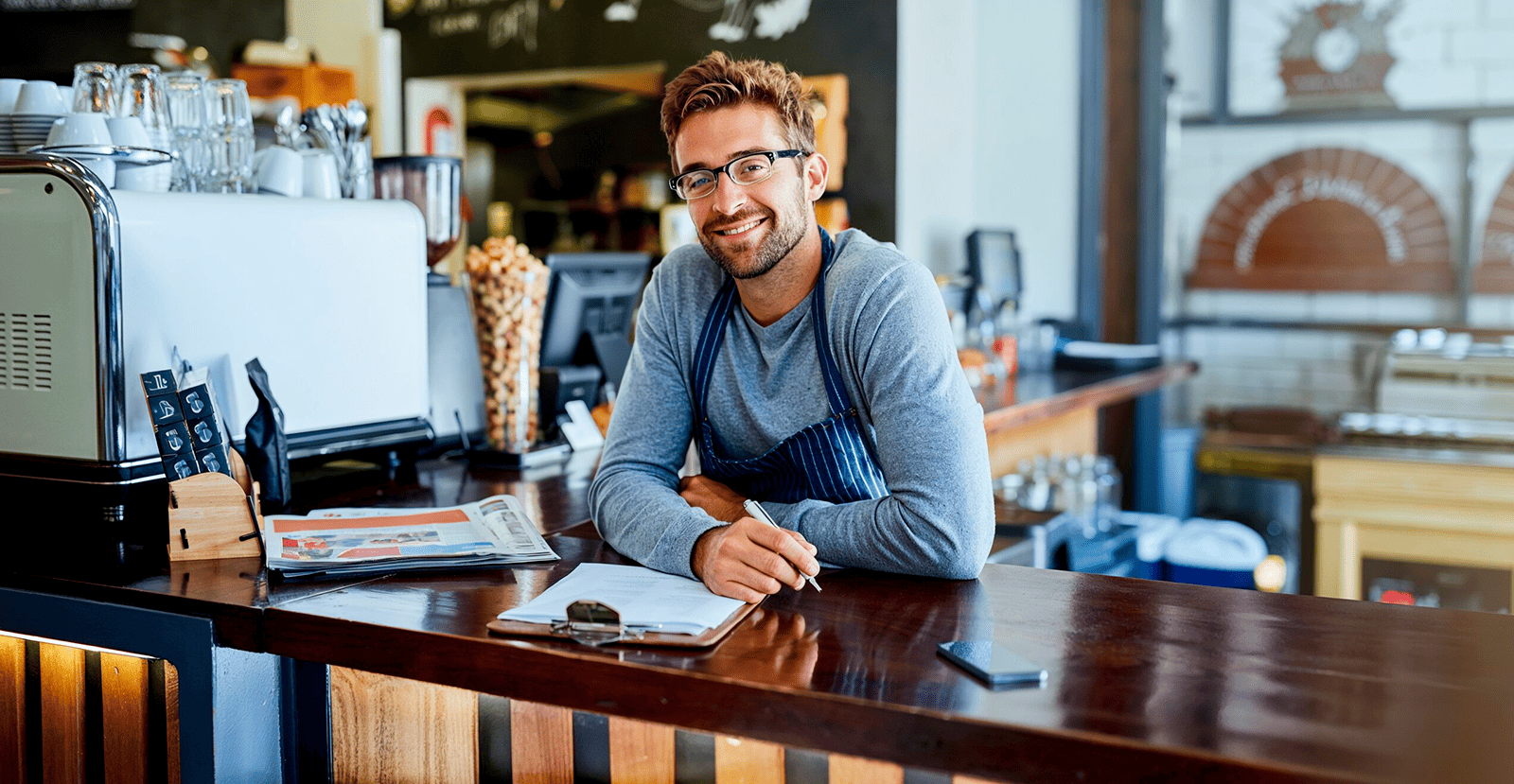 Dueño de cafetería sonriendo en el mostrador